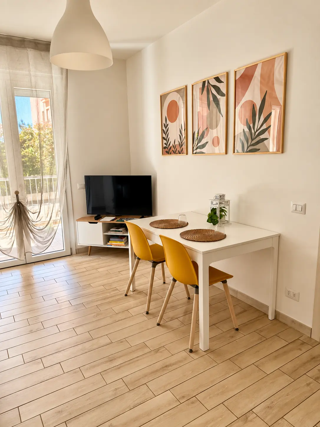 Zona pranzo con tavolo bianco, sedie gialle e Smart TV